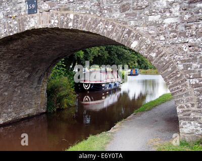 Le Monmouthshire & Brecon Canal à Pencelli avec pont de pierre pittoresque et étroite près de bateaux amarrés Marina Pencelli Banque D'Images