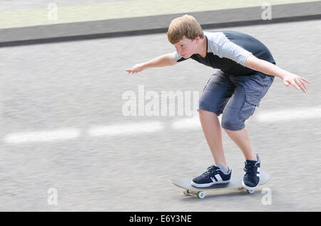 Jeune adolescent patineur guy in motion déménagement sur planche le long de route contre l'asphalte avec arrière-plan flou copier-espace salon Banque D'Images