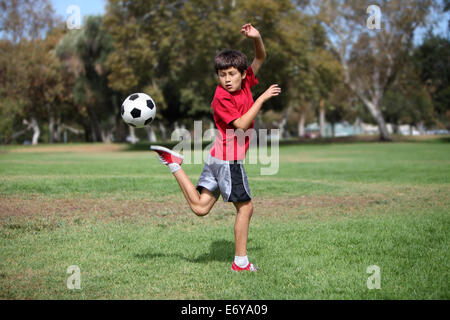 Jeune garçon joue avec un ballon de soccer pratiquer kicks - action authentique Banque D'Images