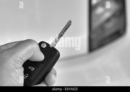 Gros plan du man's hand holding clé de voiture avec des problèmes de mise au point car en arrière-plan Banque D'Images