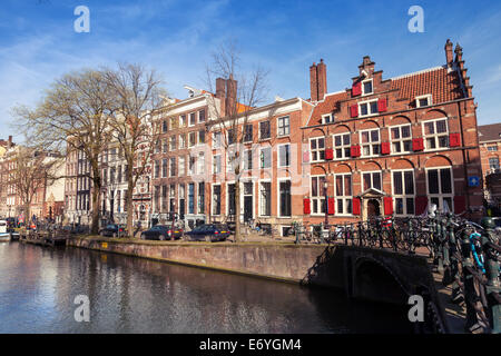 AMSTERDAM, Pays-Bas - 19 mars 2014 : maisons colorées le long de la berge du canal au printemps. Les gens ordinaires à pied Banque D'Images