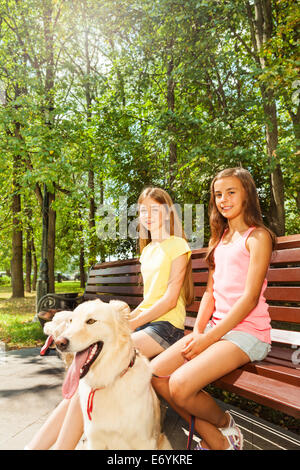 Deux filles heureux assis sur le banc dans le parc Banque D'Images