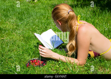 Fille lit un livre, allongé sur l'herbe verte Banque D'Images