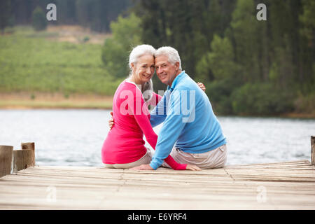Romantic senior couple assis sur une jetée Banque D'Images