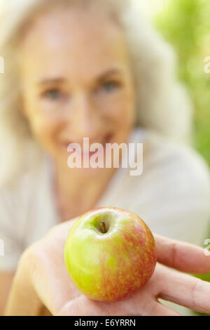 Senior woman eating apple outdoors Banque D'Images