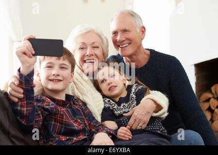 Les grands-parents et petits-enfants assis sur le canapé en prenant Selfies Banque D'Images