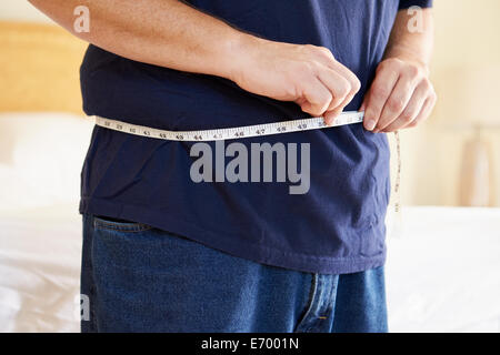 Close Up of Overweight Man Measuring Waist Banque D'Images