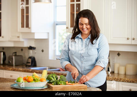 L'excès de femme préparant des légumes dans la cuisine Banque D'Images