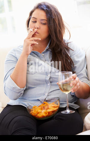 L'excès de Woman Eating Chips, boire du vin et le tabagisme Banque D'Images