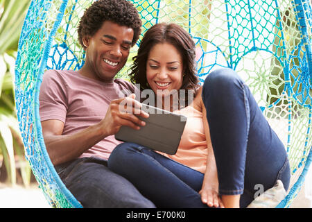 Couple sur un jardin extérieur Siège Swing Using Digital Tablet Banque D'Images