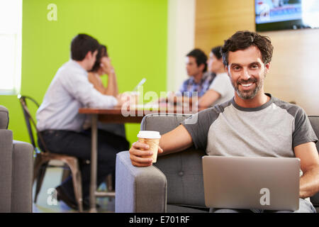 Homme assis sur un canapé et travaillant en Design Studio Banque D'Images