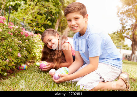 Ayant deux enfants Chasse aux Œufs de Pâques dans le jardin Banque D'Images