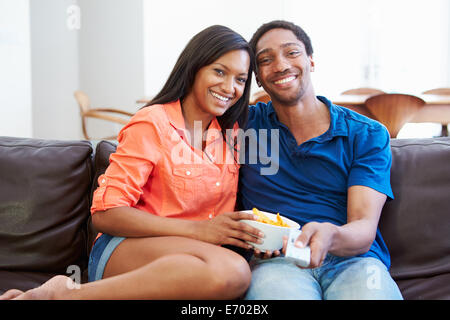 Couple assis sur le canapé à regarder la télévision ensemble Banque D'Images