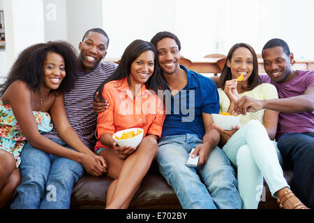 Groupe d'amis assis sur le canapé à regarder la télévision ensemble Banque D'Images