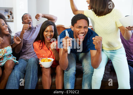 Groupe d'amis assis sur le canapé à regarder la télévision ensemble Banque D'Images