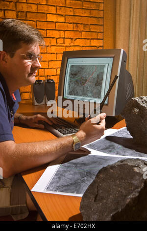 Géologue tenant un radiotéléphone tout en travaillant sur des cartes géotek d'exploration de surface et souterraine des gisements minéraux sur la mine de platine, Afrique du Sud Banque D'Images