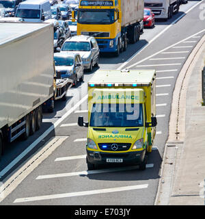 À l'aide d'ambulances d'urgence d'autoroute la plus difficile d'atteindre l'épaule de l'accident à l'avant de la circulation sur autoroute engorgée Banque D'Images