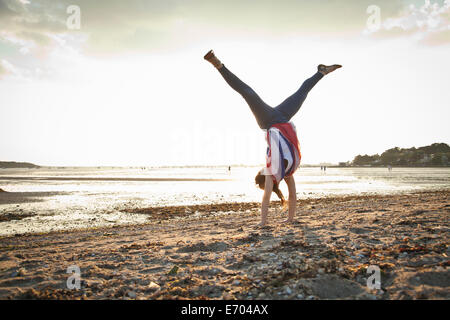 Young woman doing handstand sur la plage de Bournemouth, Dorset, UK Banque D'Images