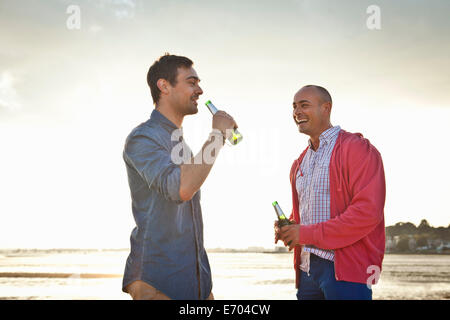 Les hommes de boire une bière et de discuter sur la plage Banque D'Images