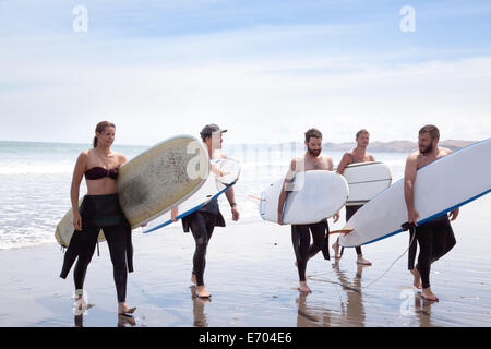 Groupe d'hommes et femmes d'amis surfeur marche loin de la mer avec des planches de surf Banque D'Images