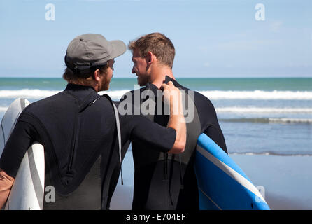 Vue arrière du surfeur homme contrôle ses amis combinaison fermeture éclair Banque D'Images