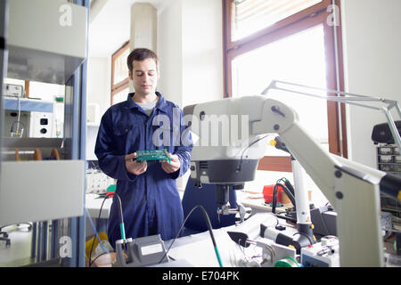 Male electrician regardant le circuit board in workshop Banque D'Images