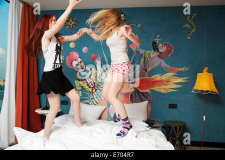 Deux jeunes femmes dancing on hotel bed Banque D'Images