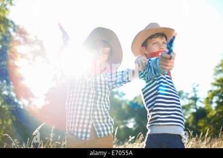 Deux jeunes garçons habillés comme des cowboys, tenant les armes-jouets Banque D'Images
