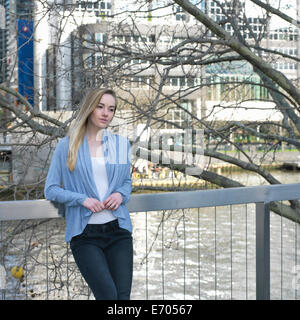 Young woman leaning against garde-fous aux city riverside Banque D'Images