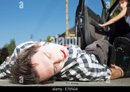 Jeune homme a frappé en voiture couchée sur road Banque D'Images