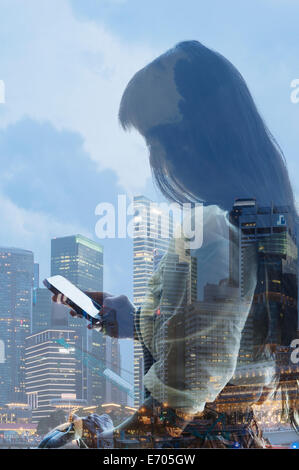 Ville et young woman using smartphone, la réflexion sur la fenêtre Banque D'Images
