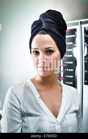 Portrait de jeune femme dans un salon de coiffure avec serviette enroulée autour de sa tête