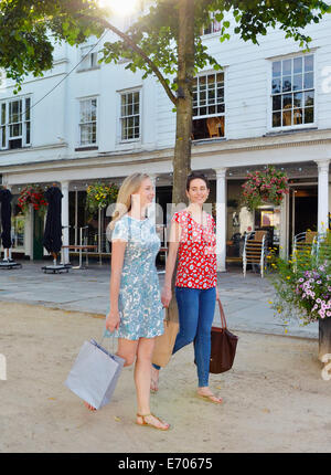 Deux jeunes femmes se promener le long de l'street carrying shopping bags Banque D'Images