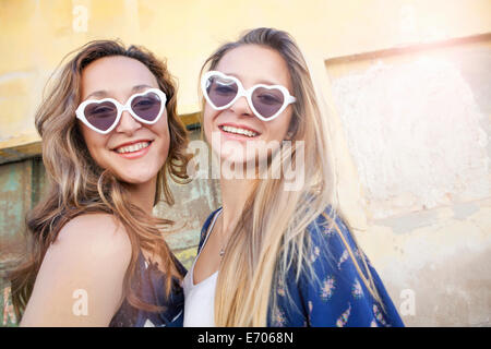 Les jeunes filles portant des lunettes de soleil en forme de cœur Banque D'Images