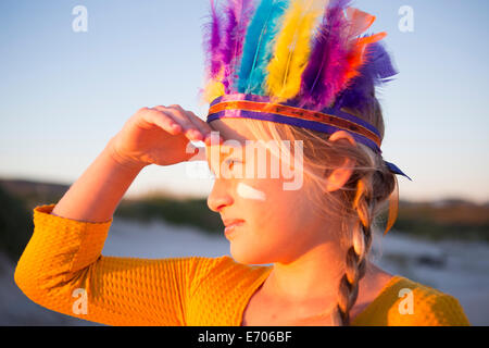 Close up of boy coiffure de plumes amérindiennes dans la main avec les yeux d'ombrage Banque D'Images