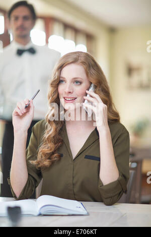 Young businesswoman chatting on smartphone in restaurant Banque D'Images