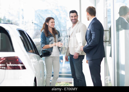 Vendeur et couple chatting in car dealership Banque D'Images
