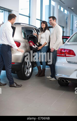 Vendeur à discuter avec famille avec baby girl in car dealership Banque D'Images