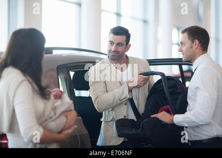 Couple avec bébé fille parler de siège bébé à l'agence de voiture Banque D'Images