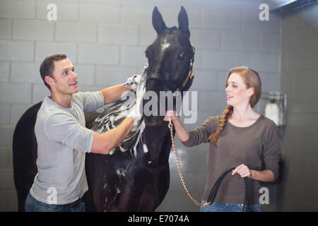 Homme et femme stablehands echelle cheval en équitation Banque D'Images