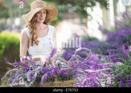 Belle jeune femme en regardant le jardin fleurs violettes Banque D'Images