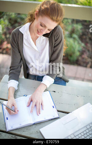 Young businesswoman writing in agenda de travail à table de jardin Banque D'Images