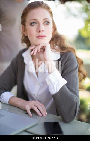 Young businesswoman with hand on chin à table de jardin Banque D'Images