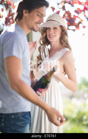 Couple prépare à célébrer avec champagne dans garden bar à vin Banque D'Images