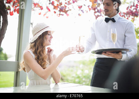 Waiter serving champagne pour jeune femme dans le garden restaurant Banque D'Images