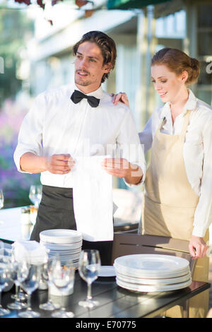 Serveur et serveuse la mise en place de tableaux dans un restaurant terrasse Banque D'Images