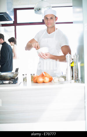 Portrait of male chef mélange avec mortier et pilon en cuisine commerciale Banque D'Images