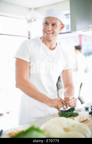 Male chef mixing Hacher les herbes en cuisine commerciale Banque D'Images