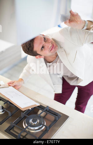 Mid adult man looking at hood in kitchen showroom Banque D'Images