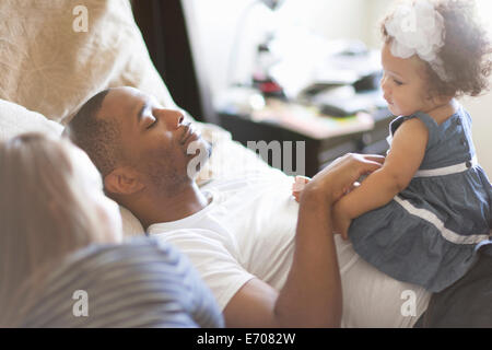Mère et père couché sur le lit avec sa petite fille